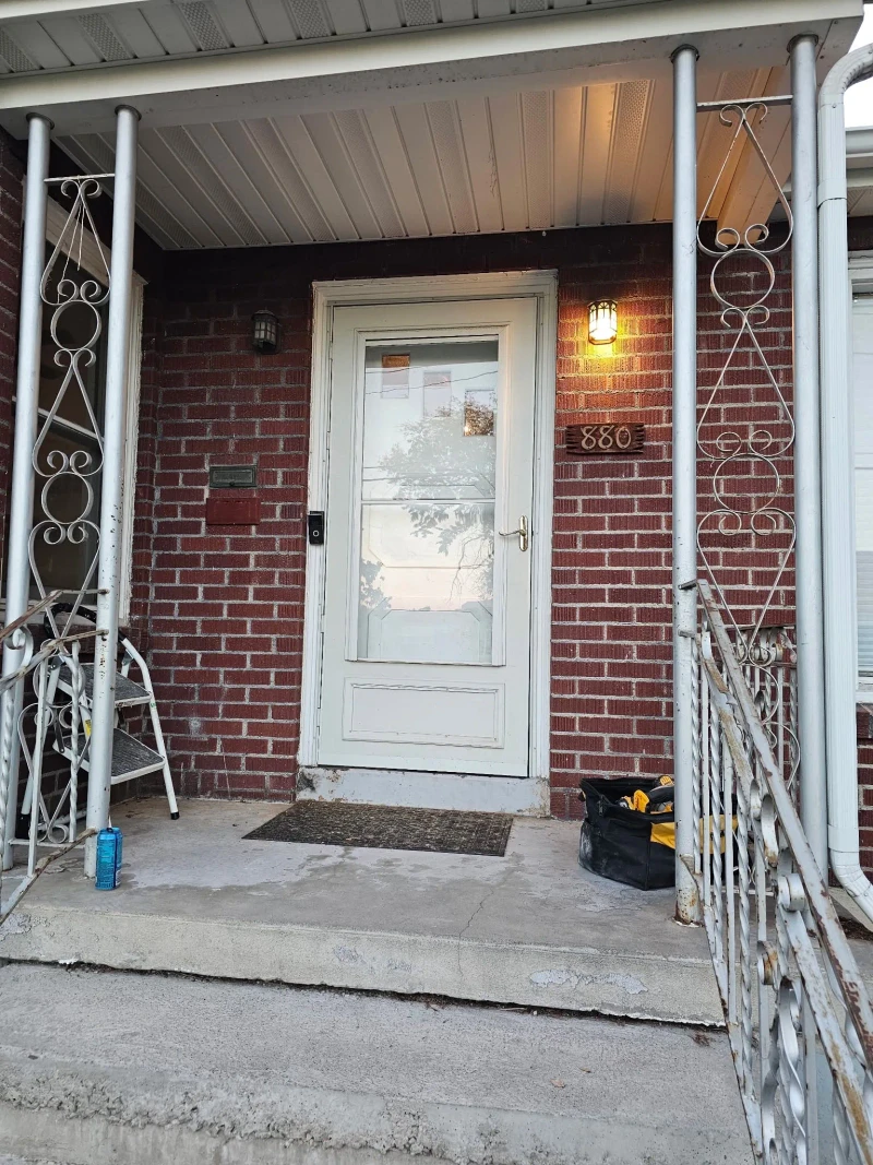 Brick front porch before the door replacement, with the old white full-glass storm door at the entry