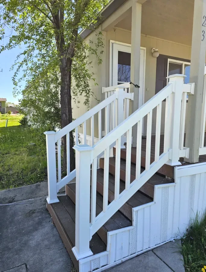 Finished white porch railing and steps at a home entrance