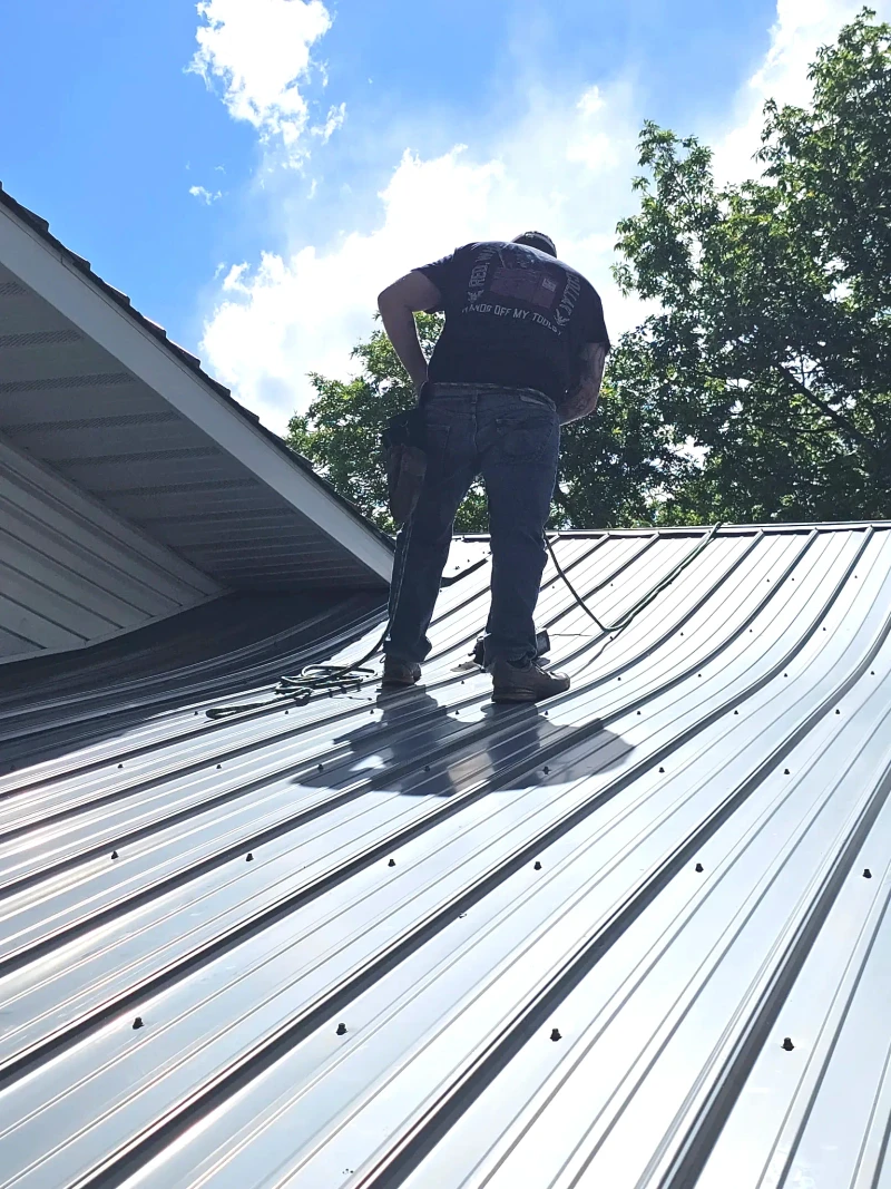 Repaired standing-seam metal roof with freshly secured panels on a sunny day